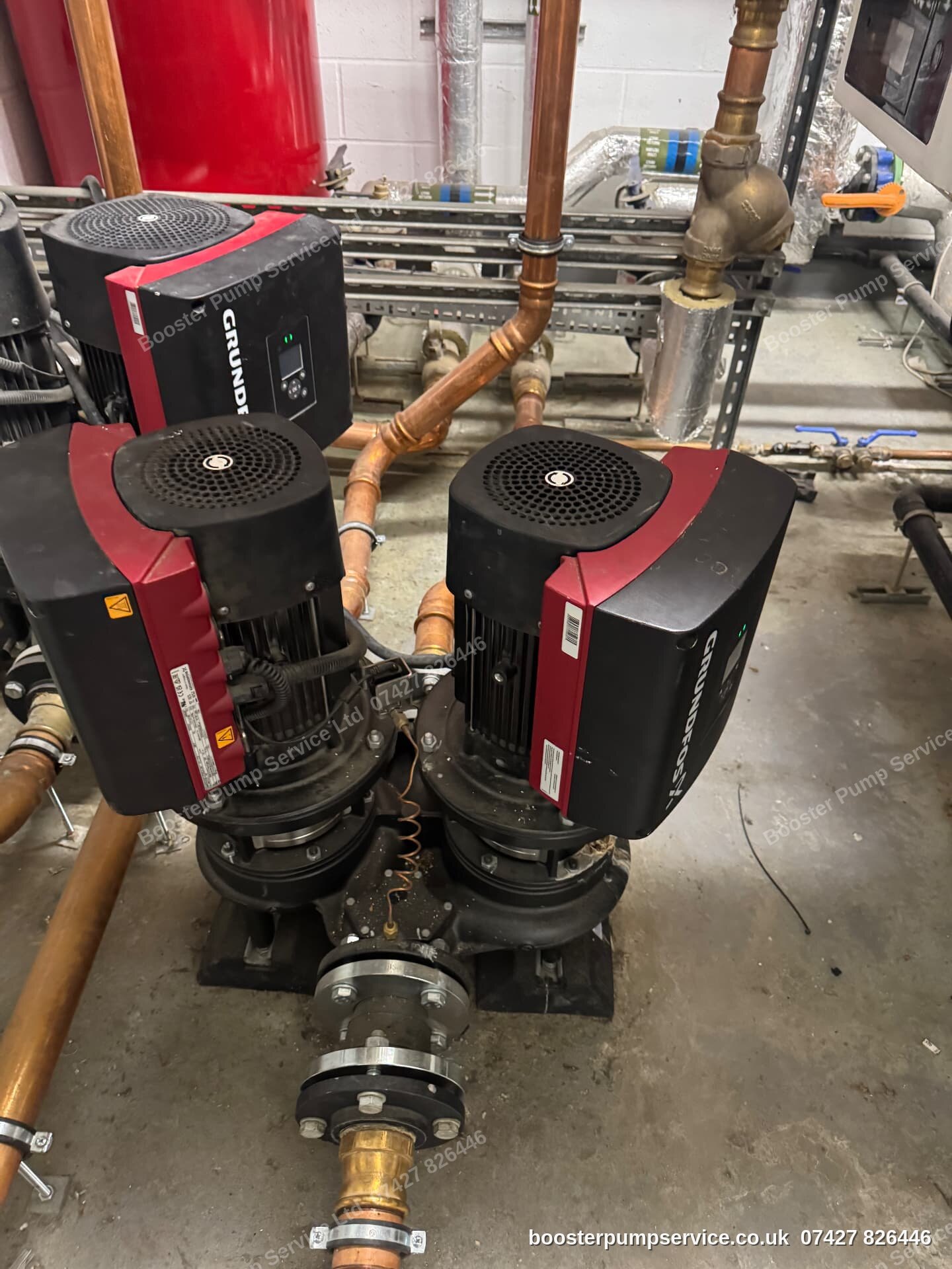 Grundfos TPE twin-head inline pumps on copper headers with a pressurisation vessel behind — inline pump replacement by our engineers in London.